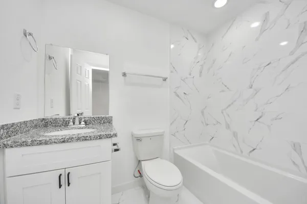 a bathroom with a granite countertop sink a toilet and a bathtub