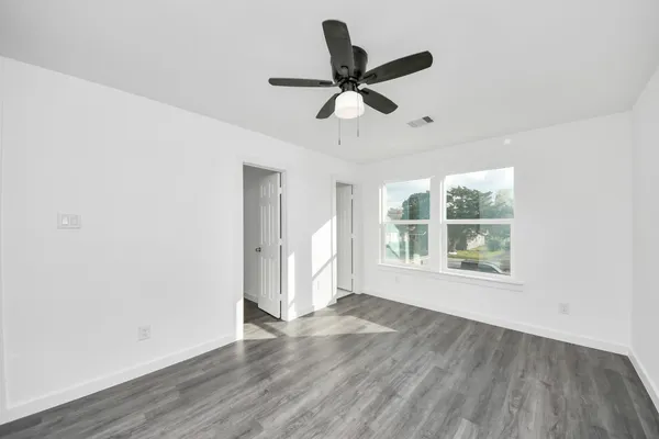 a view of empty room with wooden floor and fan