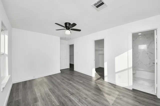 an empty room with wooden floor and a ceiling fan