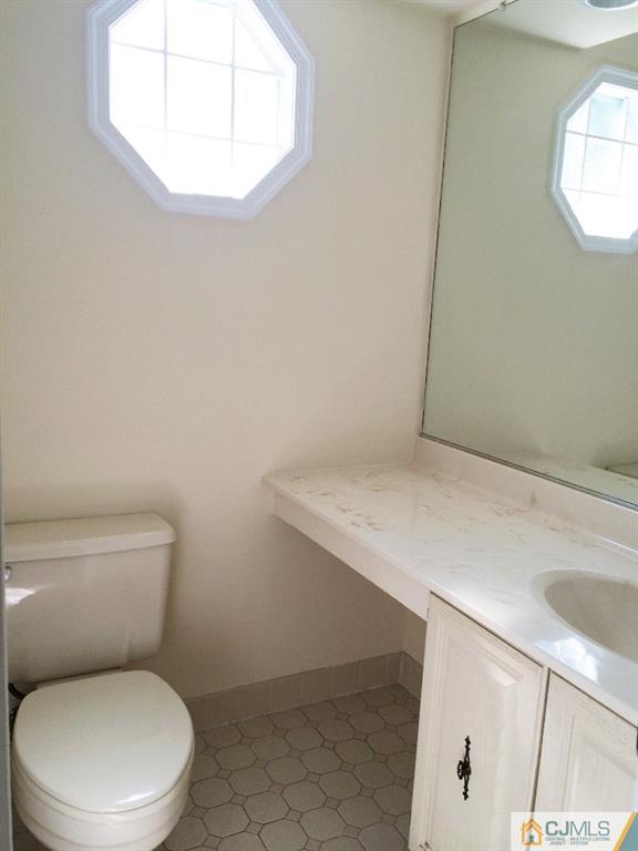 4607 Stonehedge Road Edison, NJ 08820 - Photo 10 of 10 a white toilet sitting next to a bathroom sink and vanity