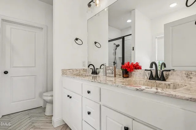 a bathroom with a granite countertop sink mirror and toilet