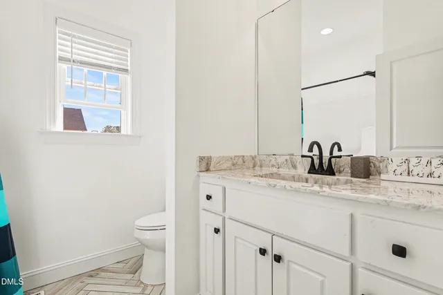 a bathroom with a granite countertop sink toilet and mirror