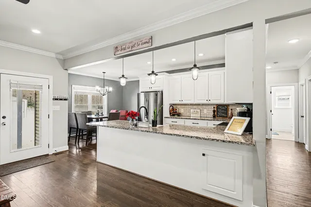 a view of a kitchen with kitchen island a sink wooden floor and living room view