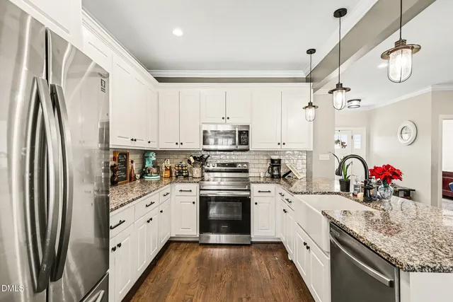 a kitchen with stainless steel appliances granite countertop a refrigerator sink and white cabinets
