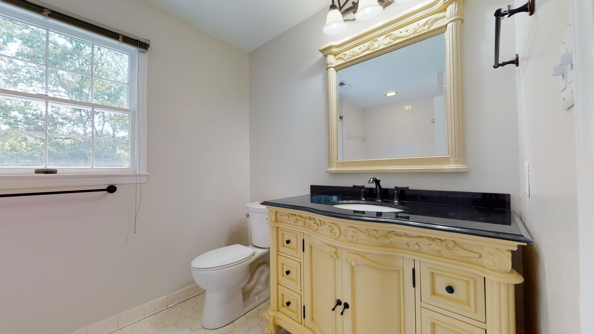 5308 Craig Road Durham, NC 27712 - Photo 46 of 46 a bathroom with a granite countertop toilet a sink and a mirror