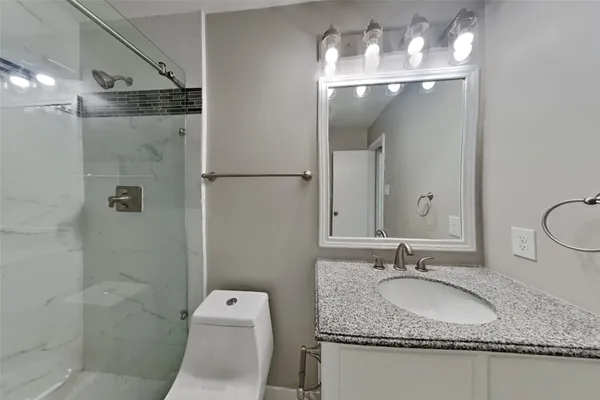a bathroom with a granite countertop sink toilet and shower