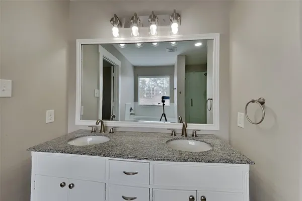 a bathroom with double vanity sinks a vanity and a light fixture