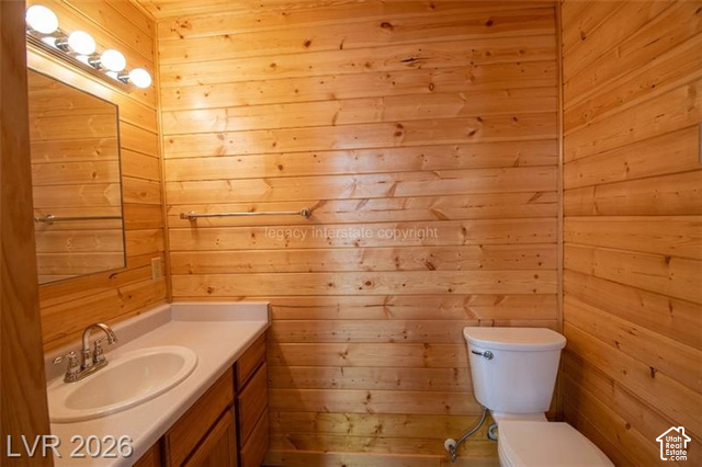 1129 Ponderosa Road, Unit 40 Hatch, UT 84735 - Photo 17 of 47 Wood-paneled walls featuring a vanity with an integrated sink, polished chrome faucet, and a wall-mounted mirror