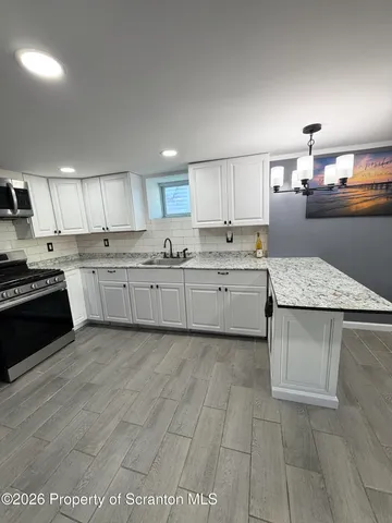 a kitchen with stainless steel appliances granite countertop a refrigerator a stove a sink and a microwave