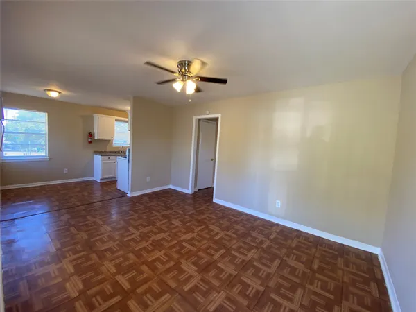 a view of empty room with wooden floor and ceiling fan