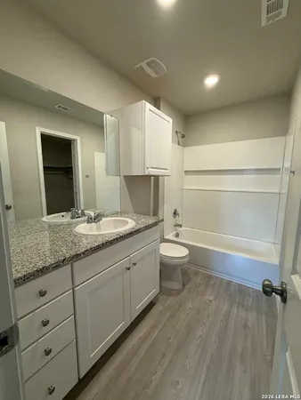 a bathroom with a granite countertop toilet a sink and a bathtub