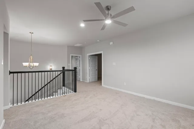 an empty room with staircase and fan
