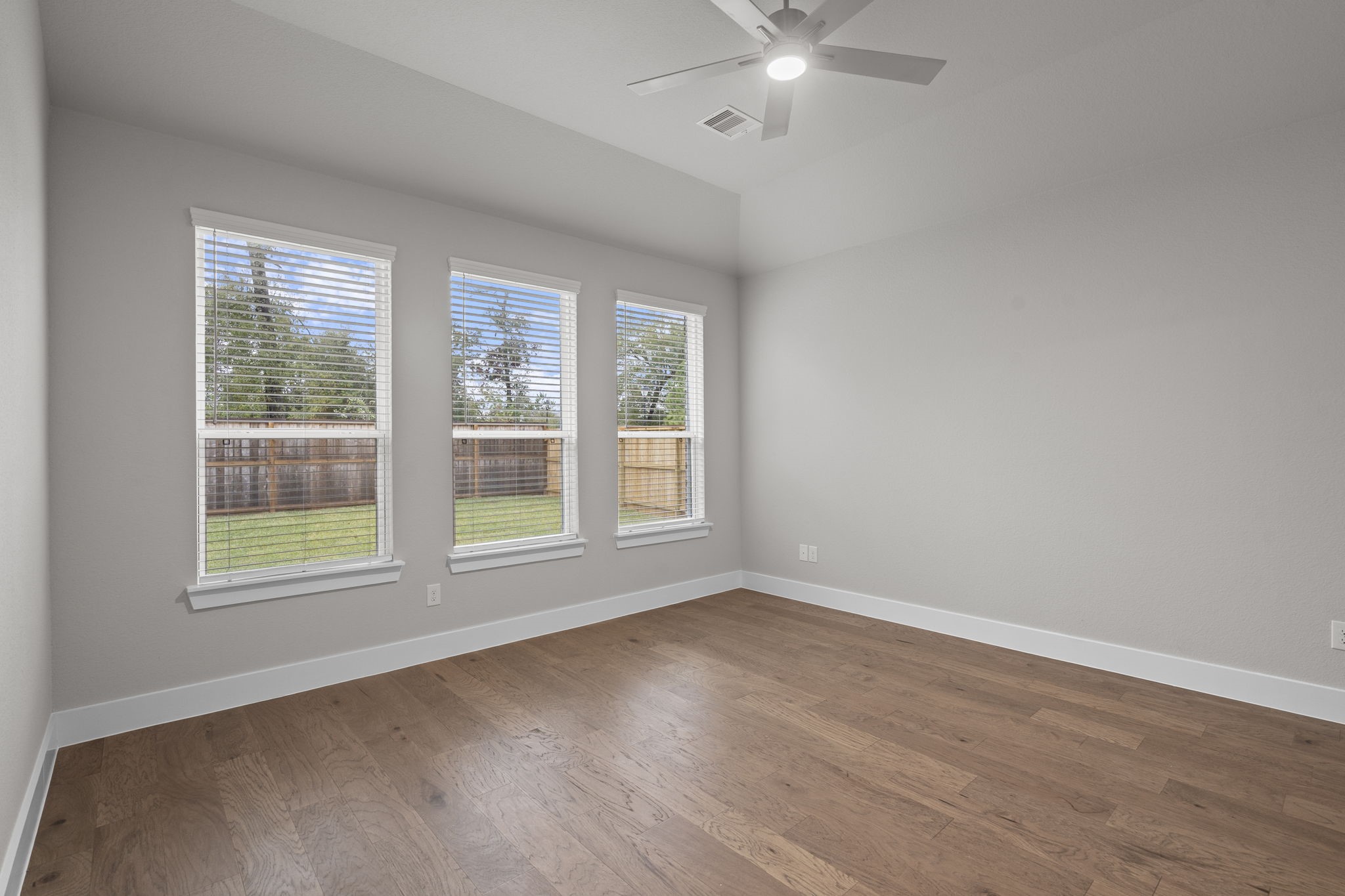 2116 Golden Spruce Court Conroe, TX 77301 - Photo 17 of 28 an empty room with wooden floor fan and windows