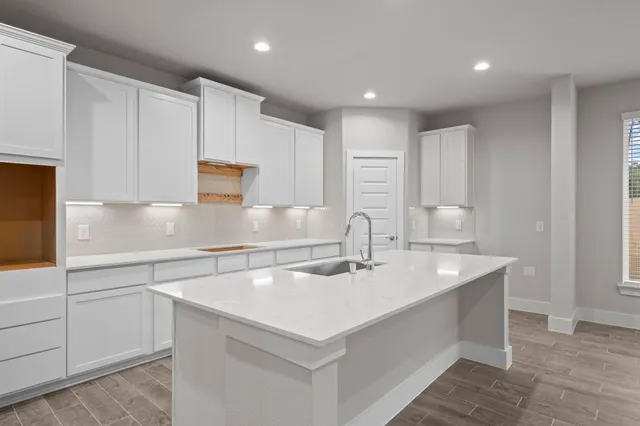 a kitchen with kitchen island a sink a center island and cabinets