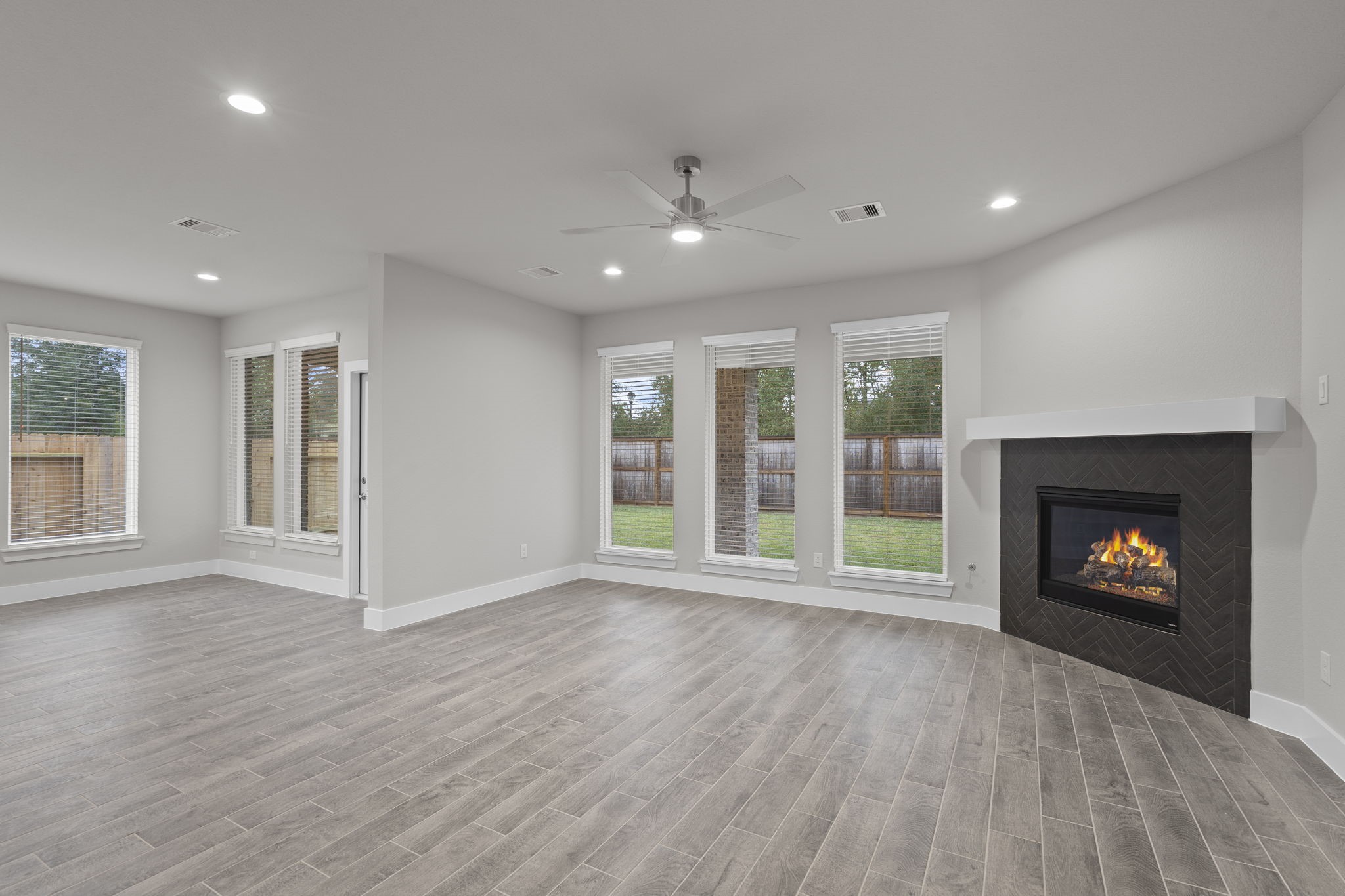 2116 Golden Spruce Court Conroe, TX 77301 - Photo 10 of 28 an empty room with windows a fireplace and wooden floor