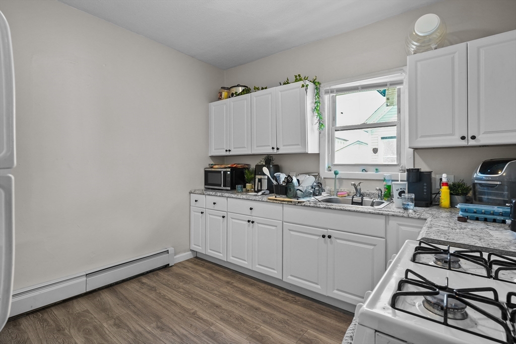 32 Quequechan Street Fall River, MA 02723 - Photo 3 of 34 a kitchen with stainless steel appliances white cabinets and a stove top oven