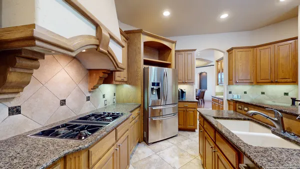 a kitchen with stainless steel appliances granite countertop a stove a sink dishwasher and refrigerator with wooden cabinets