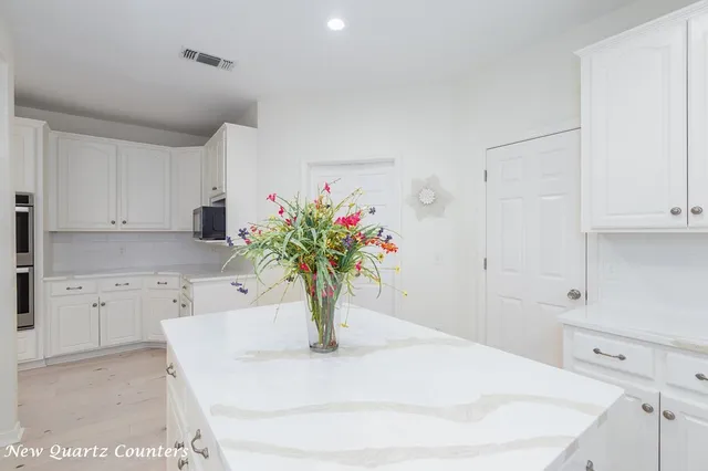 a kitchen with granite countertop white cabinets and window