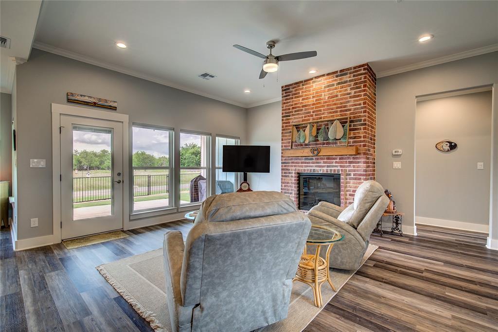 326 Koby Circle Sulphur Springs, TX 75482 - Photo 6 of 38 Living room has back door to your covered porch, one-touch window shades, beautiful brick fireplace for cozy evenings