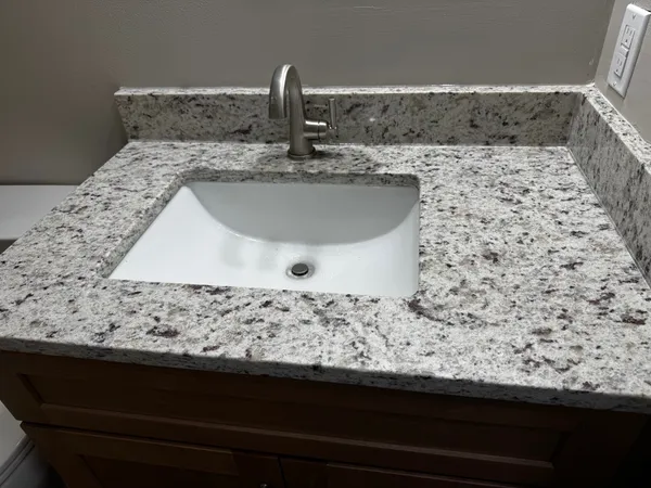 a bathroom with a granite countertop sink and a granite