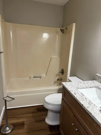 a bathroom with a granite countertop bathtub shower sink vanity and toilet