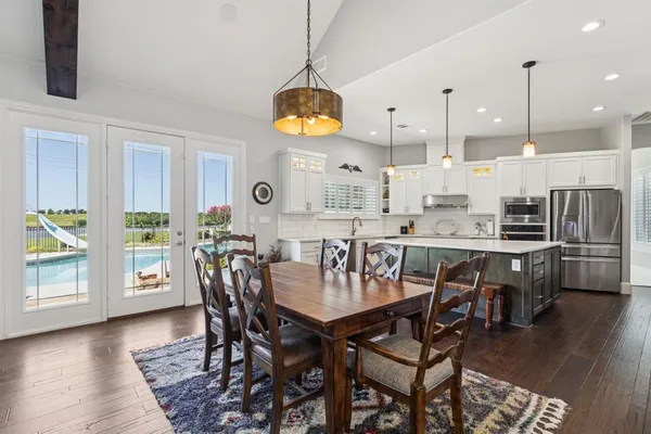 a dining room with stainless steel appliances kitchen island a table chairs and a chandelier