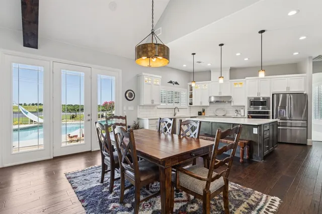a dining room with stainless steel appliances kitchen island a table chairs and a chandelier