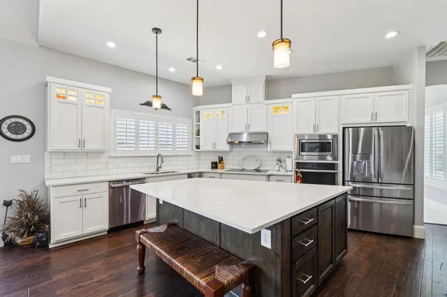 a kitchen with a refrigerator a sink and wooden floor