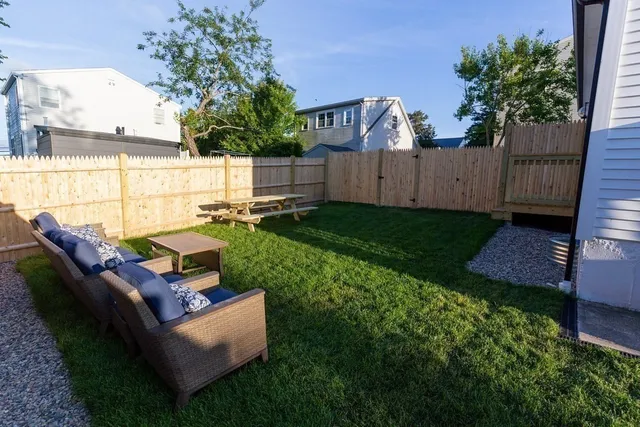 a view of a patio with couches chairs and a fire pit with wooden fence
