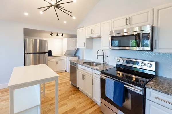 a kitchen with stainless steel appliances a stove a sink and white cabinets