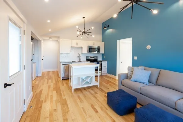 a living room with stainless steel appliances kitchen island granite countertop furniture and a wooden floor