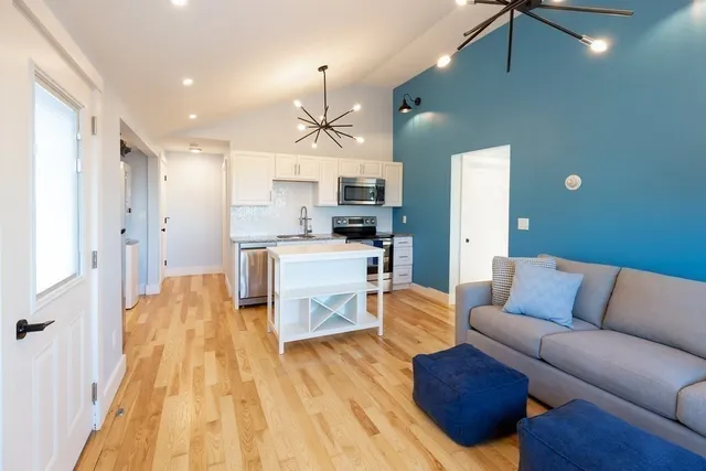 a living room with stainless steel appliances kitchen island granite countertop furniture and a wooden floor