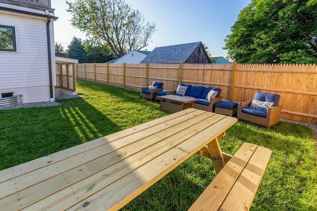 a view of a patio with couches chairs and a fire pit with wooden fence