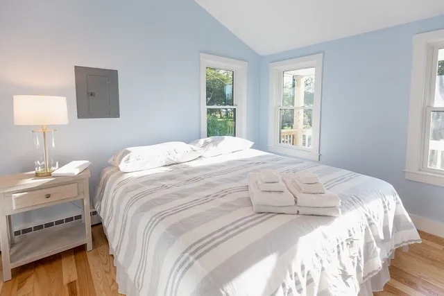 a large white bed in a bedroom next to a window