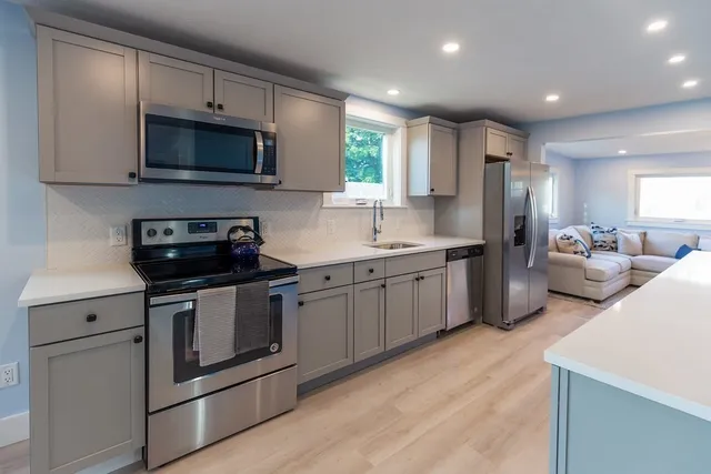 a kitchen with stainless steel appliances granite countertop a sink a stove a refrigerator and a microwave