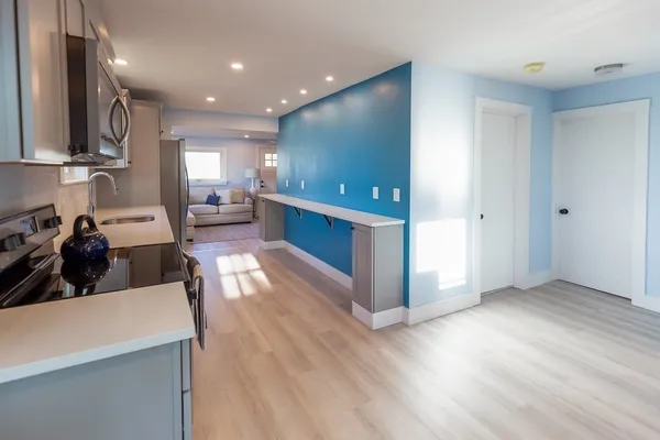 a living room with stainless steel appliances furniture wooden floor and a view of kitchen