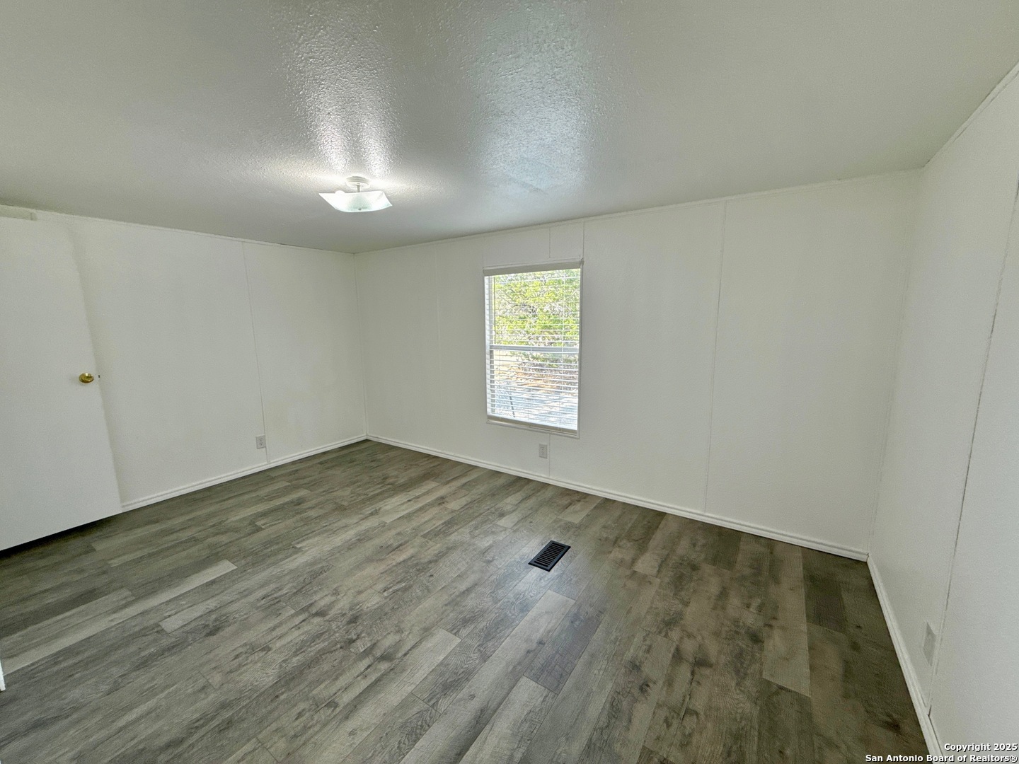 300 Pecos Road Bandera, TX 78003 - Photo 19 of 44 an empty room with wooden floor and windows