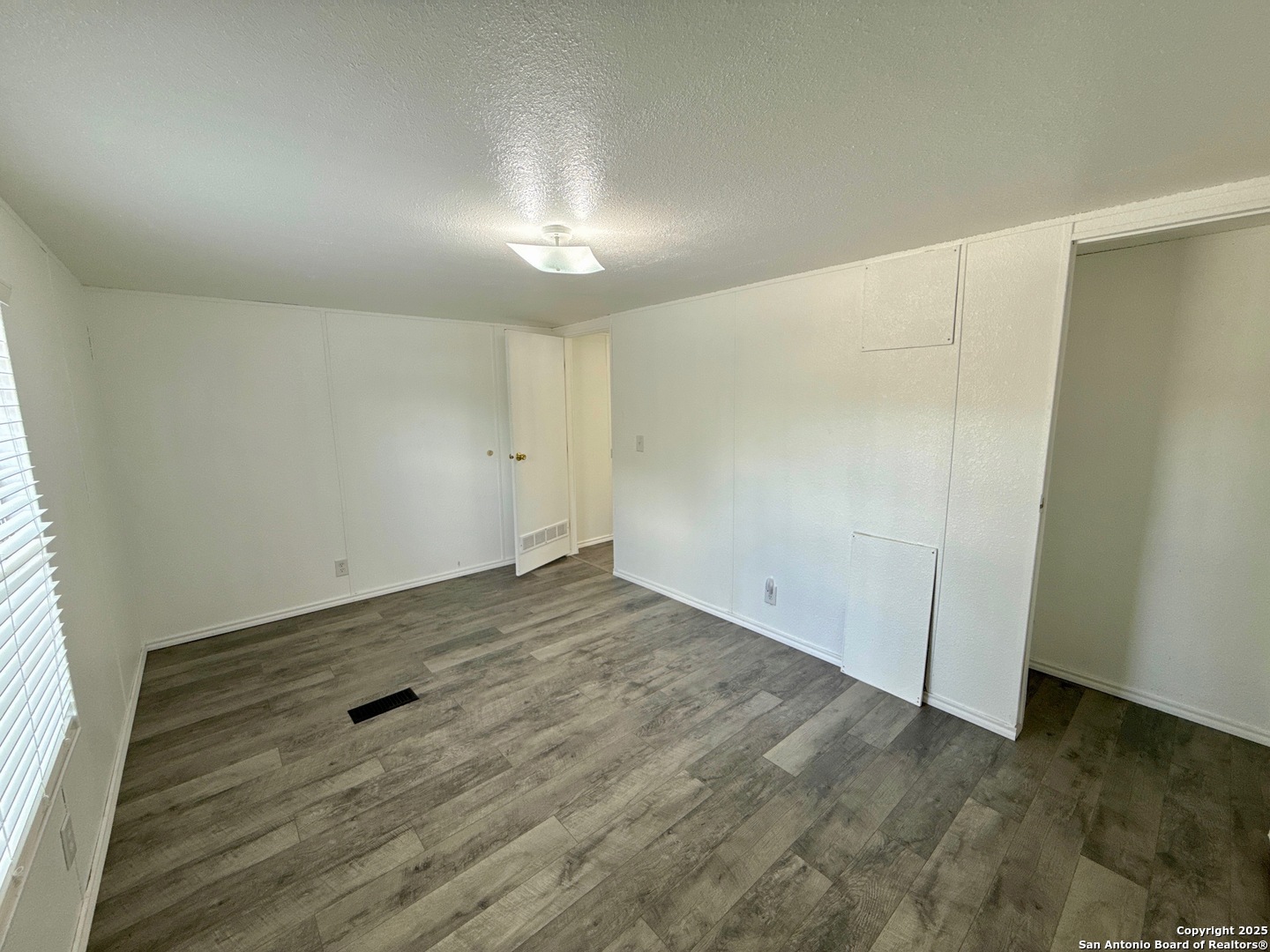 300 Pecos Road Bandera, TX 78003 - Photo 20 of 44 an empty room with wooden floor and windows