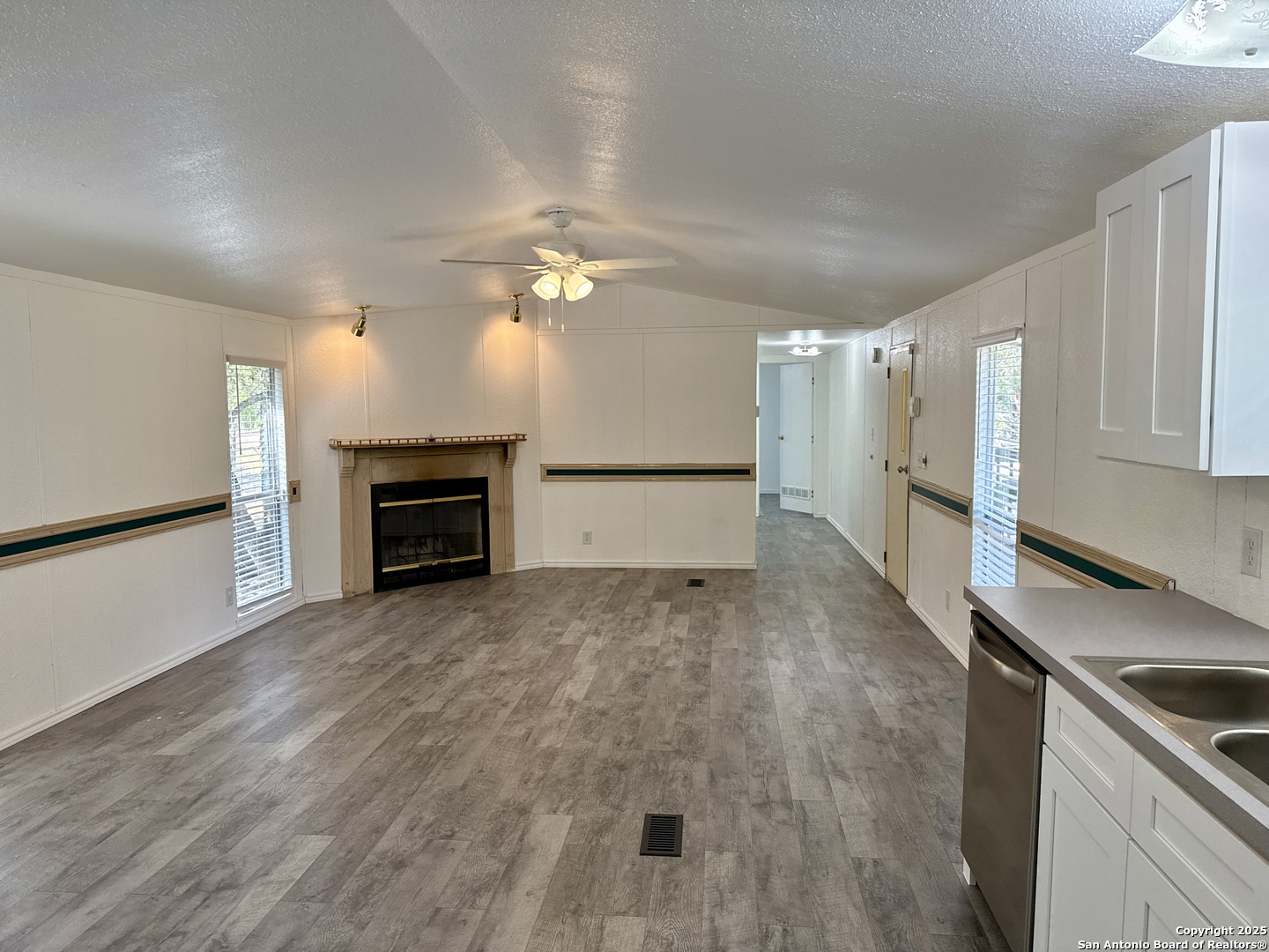 300 Pecos Road Bandera, TX 78003 - Photo 6 of 44 an empty room with wooden floor fireplace and windows