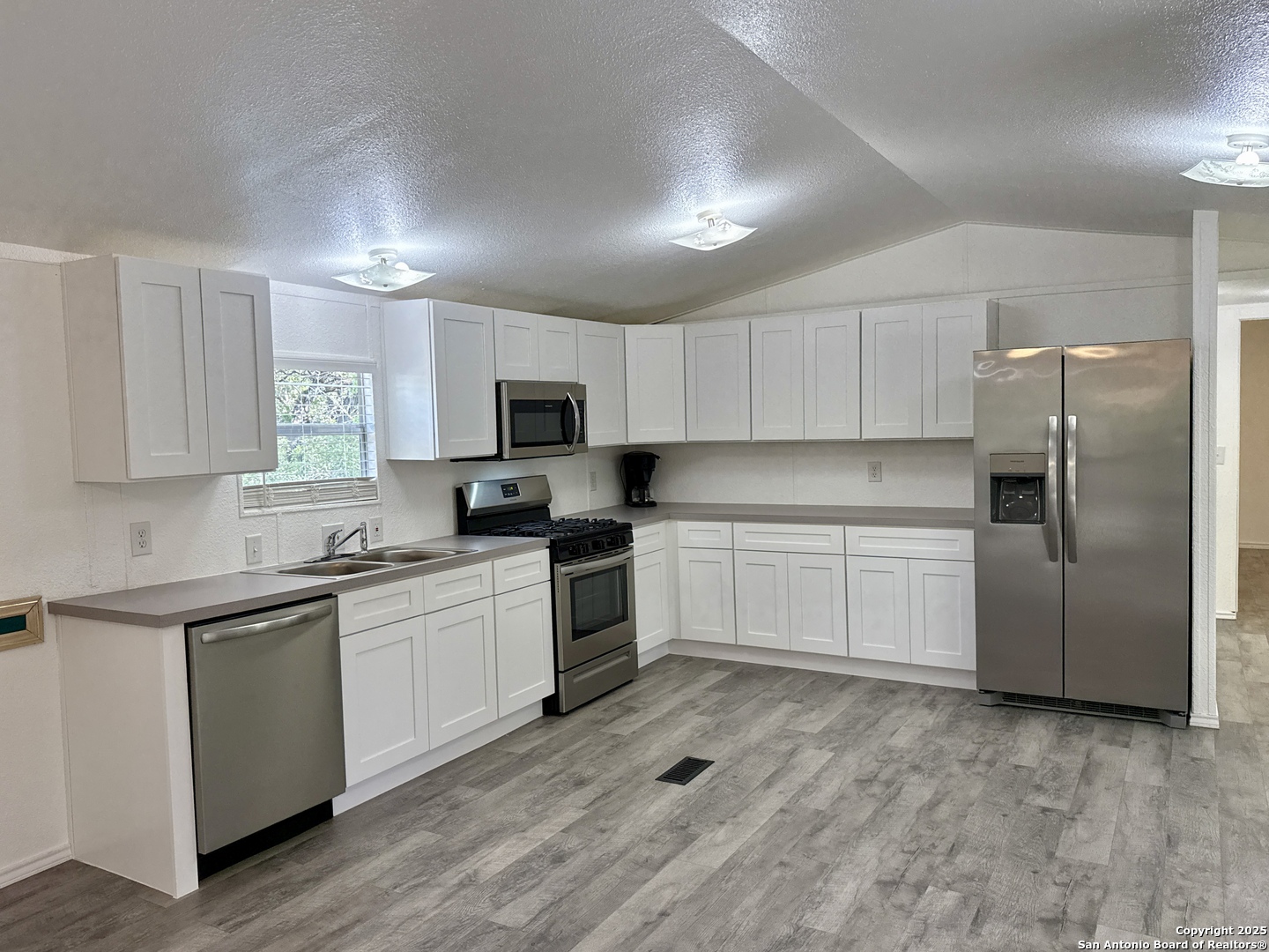 300 Pecos Road Bandera, TX 78003 - Photo 8 of 44 a kitchen with granite countertop a refrigerator sink and wooden cabinets