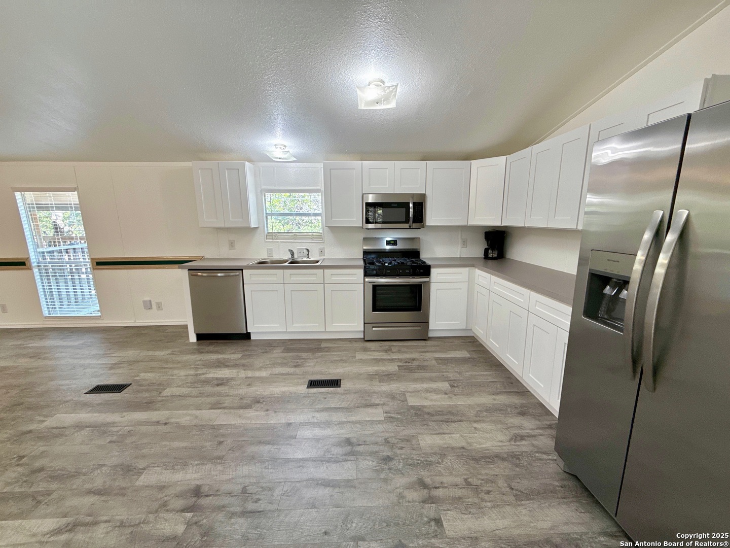 300 Pecos Road Bandera, TX 78003 - Photo 9 of 44 a kitchen with stainless steel appliances granite countertop a stove top oven a sink a refrigerator and white cabinets