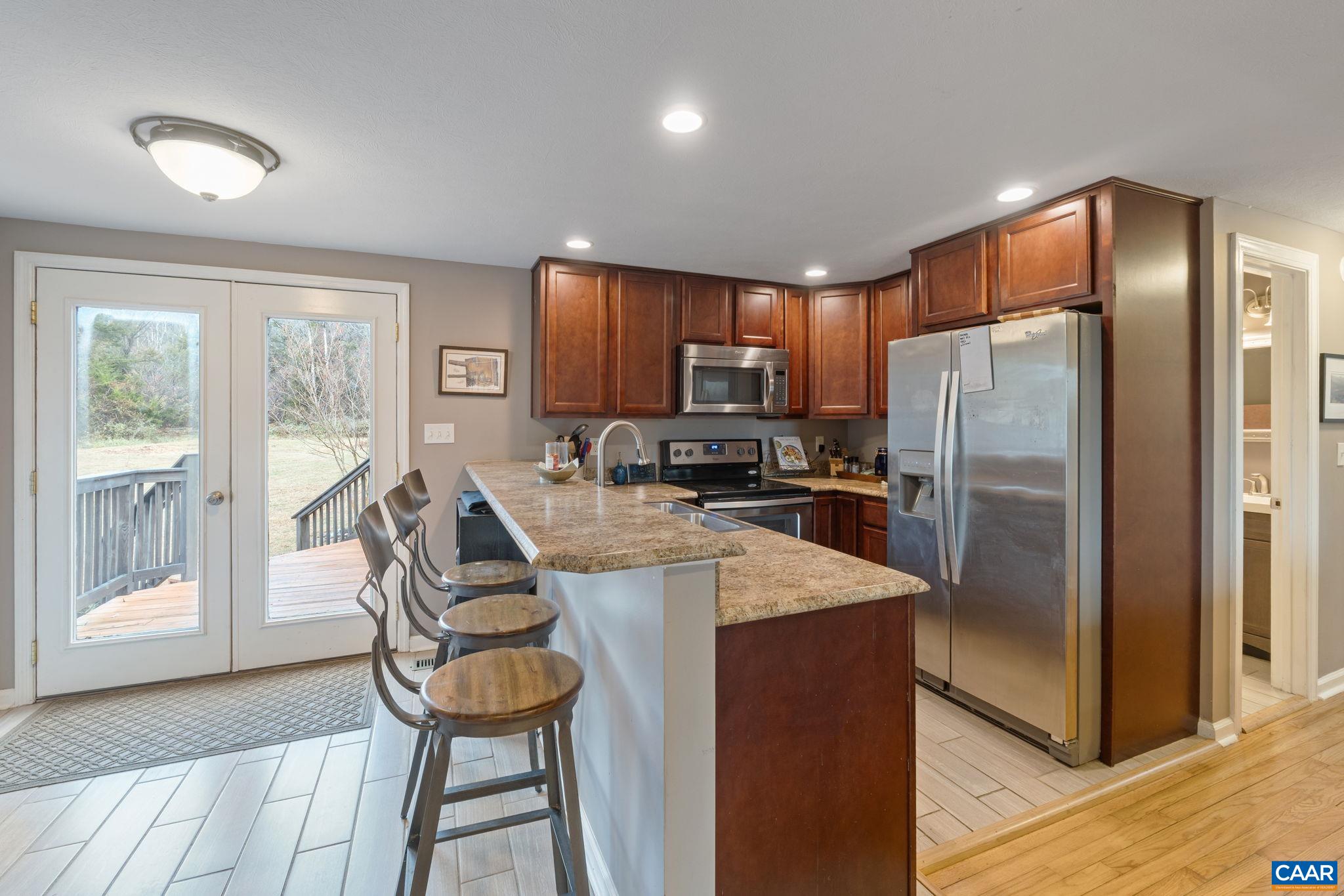 504 Newtown Road Greenwood, VA 22943 - Photo 8 of 34 a kitchen with granite countertop a refrigerator a stove a sink and a dining table with wooden floor