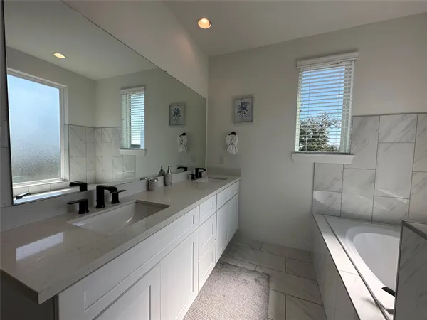 a bathroom with double vanity and a bathtub