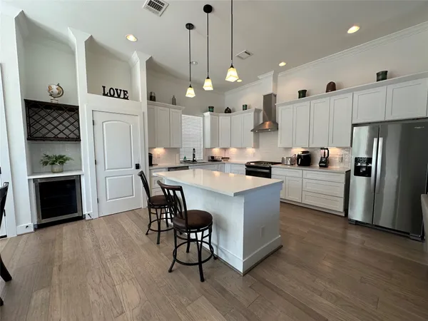 a kitchen with kitchen island a refrigerator a stove a microwave oven a dining table and chairs with wooden floor