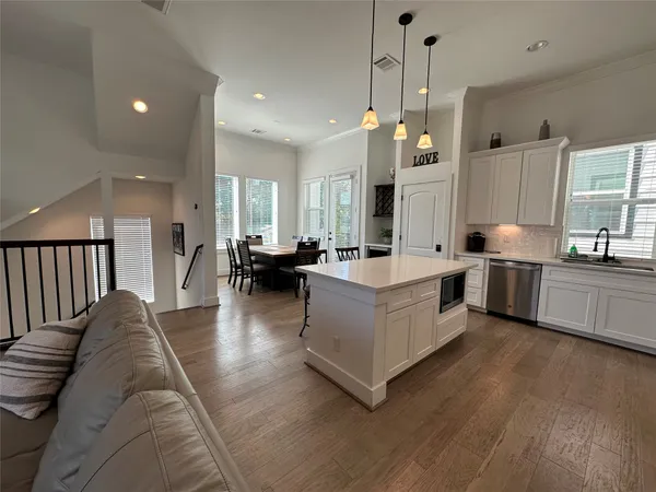 a living room with furniture kitchen area and a wooden floor