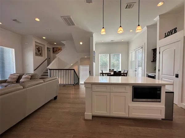 a large white kitchen with a large island oven a stove and a sink with wooden floor