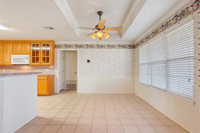 a view of an empty room with window and chandelier fan