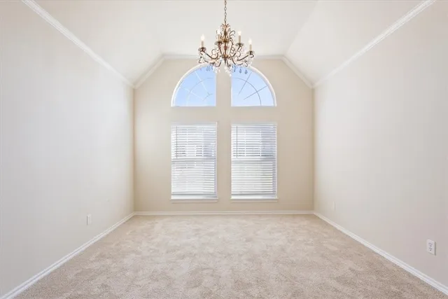 an empty room with chandelier fan and windows