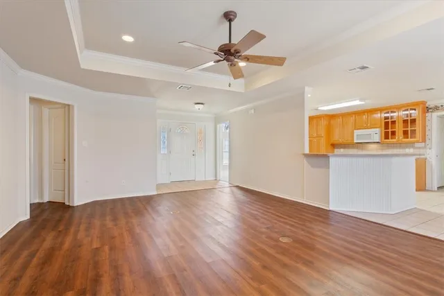 a view of an empty room with wooden floor and a ceiling fan