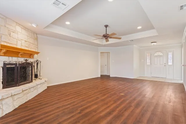 a view of an empty room with wooden floor and a kitchen